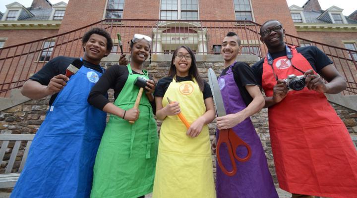 art force five club members in colorful aprons and craft tools posing for the camera